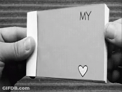 A Black And White Photo Of A Person Holding A Piece Of Paper With The Word `` My '' And A Heart Drawn On It . GIF