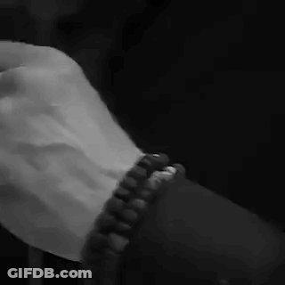 A Black And White Photo Of A Person Holding Another Person 'S Hand While Wearing A Bracelet . GIF