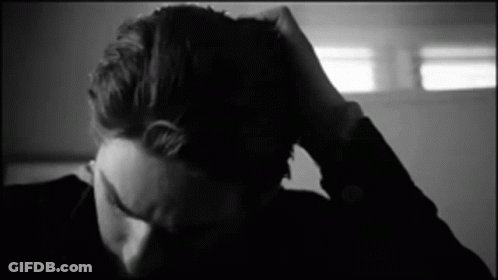 A Black And White Photo Of A Person Holding Their Head . GIF