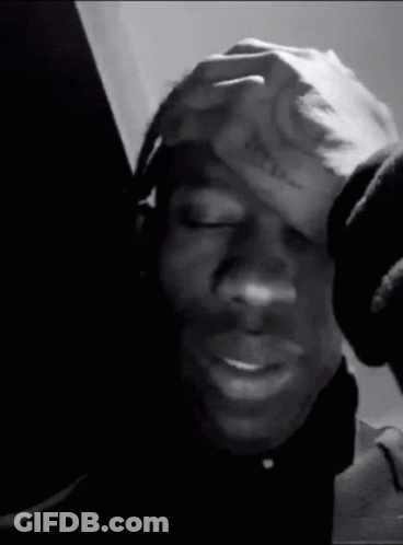 A Black And White Photo Of A Person Holding Their Head . GIF