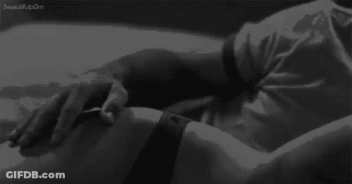 A Black And White Photo Of A Person Laying On A Bed With Their Hands On Their Stomach . GIF