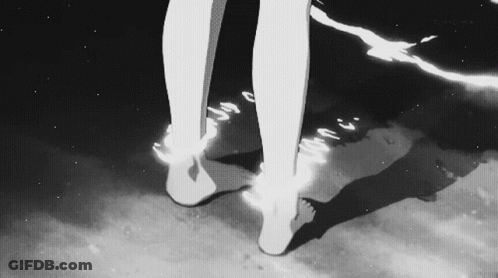 A Black And White Photo Of A Person 'S Feet Standing On A Beach . GIF