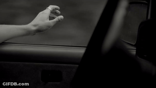A Black And White Photo Of A Person 'S Hand Reaching Out From A Car Window GIF