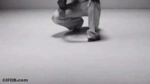 A Black And White Photo Of A Person Squatting On A White Surface GIF