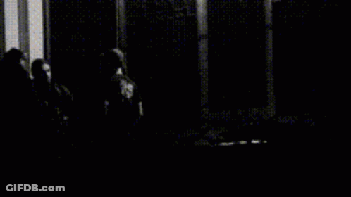 A Black And White Photo Of A Person Standing On Stairs At Night GIF