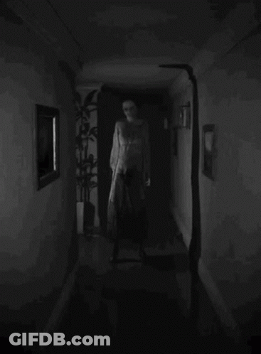 A Black And White Photo Of A Person Walking Down A Hallway GIF