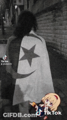 A Black And White Photo Of A Person Wearing A Cape With A Black Star On It GIF