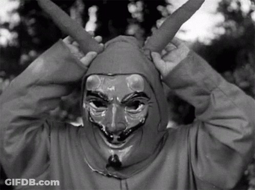 A Black And White Photo Of A Person Wearing A Devil Mask And A Hood . GIF