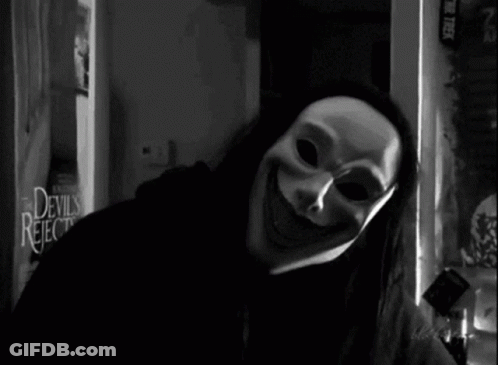 A Black And White Photo Of A Person Wearing A Mask In Front Of A Devils Rejects Sign GIF
