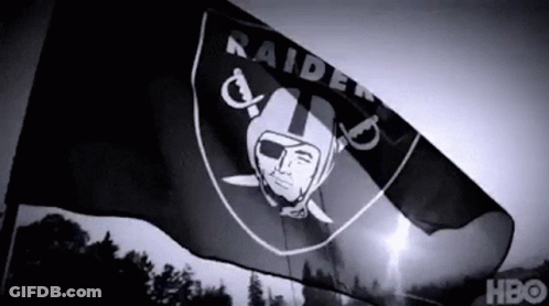 A Black And White Photo Of A Raiders Flag Flying In The Wind GIF