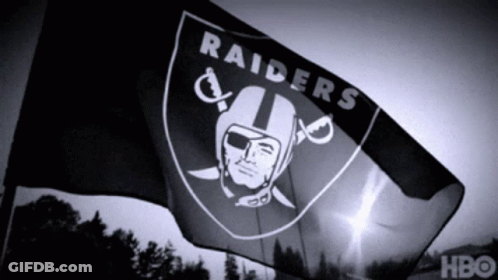A Black And White Photo Of A Raiders Flag Waving In The Wind GIF