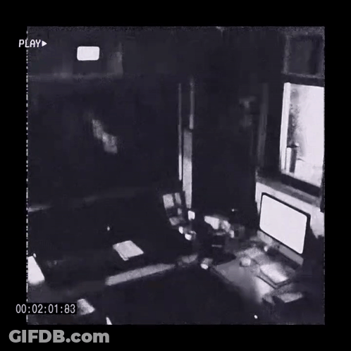A Black And White Photo Of A Room With A Computer And A Clock GIF
