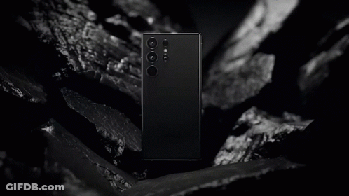 A Black And White Photo Of A Samsung Phone Laying On A Rock GIF