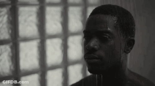 A Black And White Photo Of A Shirtless Man Taking A Shower In Front Of A Window . GIF