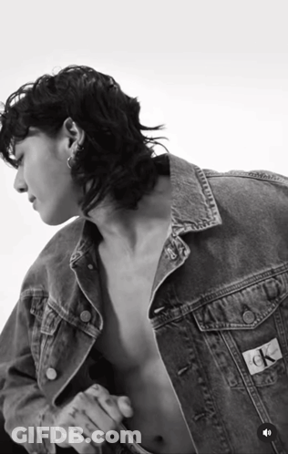 A Black And White Photo Of A Shirtless Man Wearing A Denim Jacket That Says Ck On The Back GIF