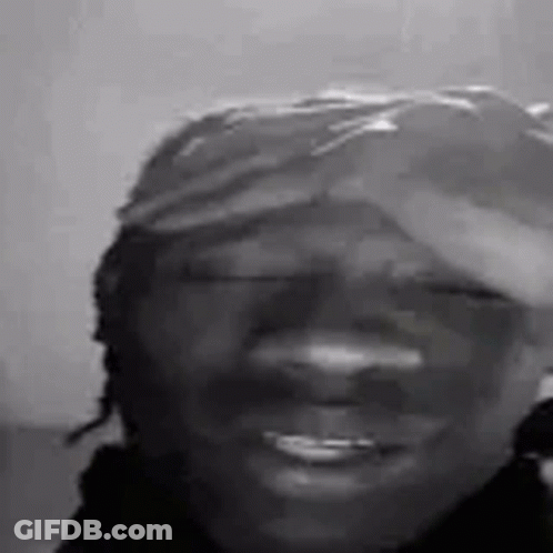 A Black And White Photo Of A Smiling Man Wearing A Hat . GIF