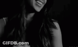 A Black And White Photo Of A Smiling Woman In A Dark Room . GIF