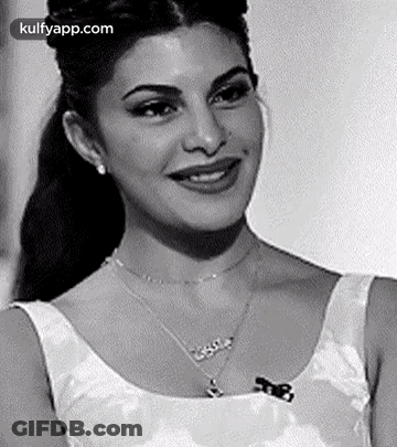 A Black And White Photo Of A Smiling Woman Wearing A Necklace And Earrings . GIF