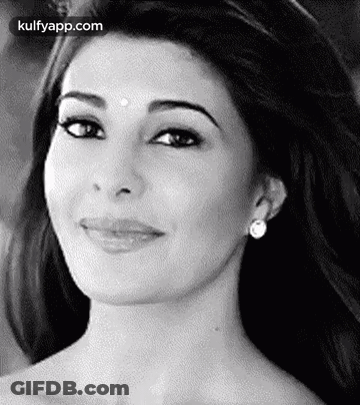 A Black And White Photo Of A Smiling Woman Wearing Earrings And A Bindi On Her Forehead . GIF