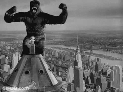 A Black And White Photo Of A Statue Of A Gorilla On Top Of A Building GIF