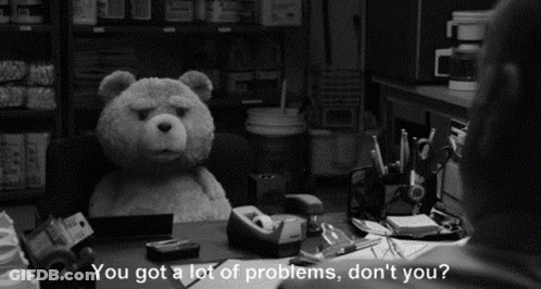 A Black And White Photo Of A Teddy Bear Sitting At A Desk With A Man Talking To It . GIF