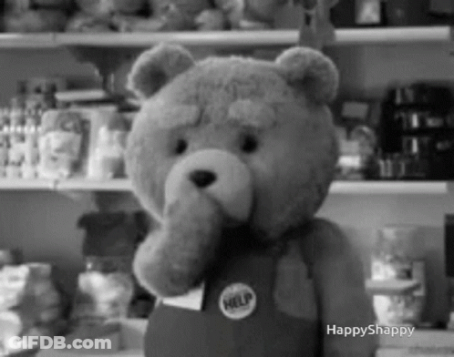 A Black And White Photo Of A Teddy Bear Wearing Overalls And A Help Badge . GIF