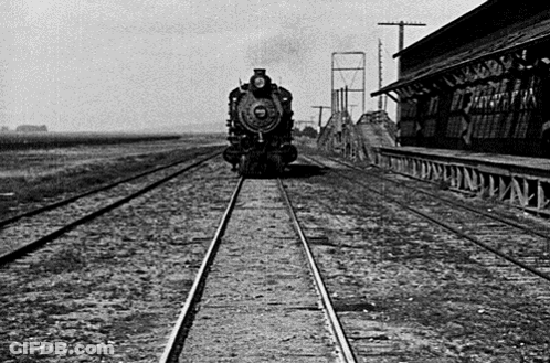A Black And White Photo Of A Train On The Tracks GIF
