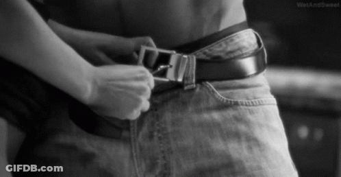 A Black And White Photo Of A Woman Adjusting A Belt On A Man 'S Waist . GIF