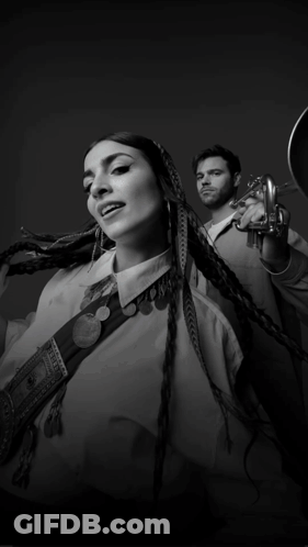 A Black And White Photo Of A Woman And A Man Playing Trumpets GIF