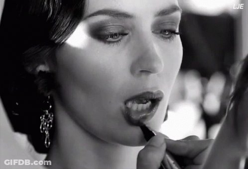 A Black And White Photo Of A Woman Applying Lipstick With The Letters Lje In The Corner GIF