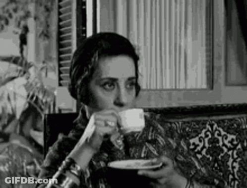 A Black And White Photo Of A Woman Drinking From A Cup . GIF