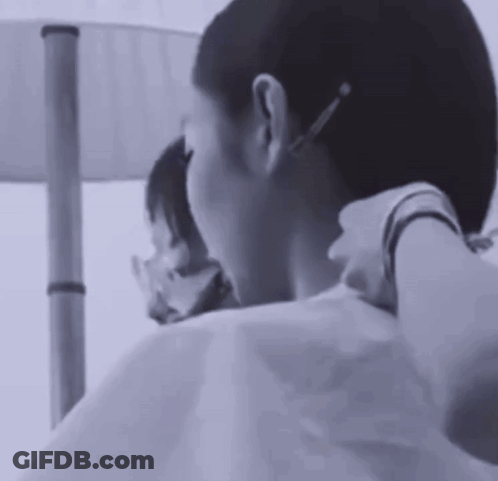 A Black And White Photo Of A Woman Getting Her Hair Cut By A Hairdresser . GIF