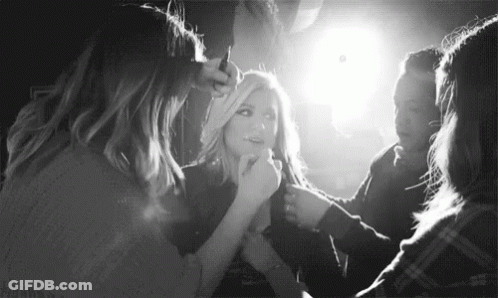 A Black And White Photo Of A Woman Getting Her Hair Done By A Group Of Women . GIF