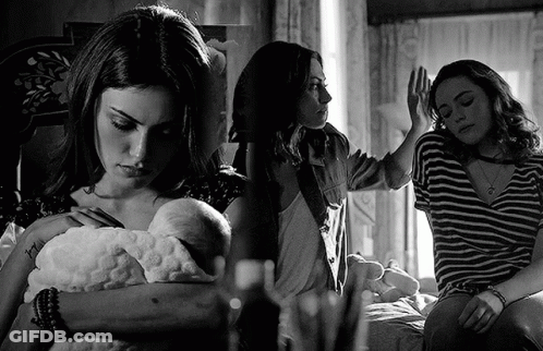 A Black And White Photo Of A Woman Holding A Baby And Another Woman Sitting On A Bed . GIF