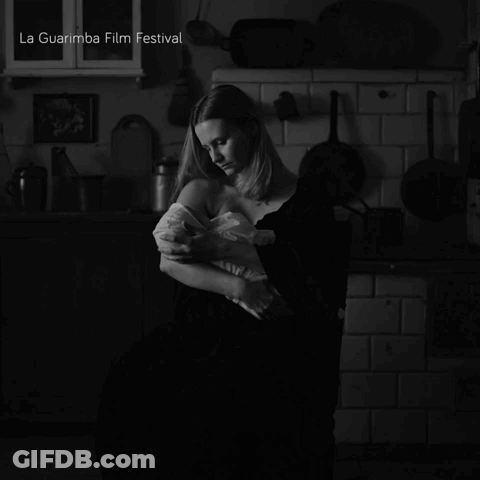 A Black And White Photo Of A Woman Holding A Baby With La Guarimba Film Festival In The Corner GIF