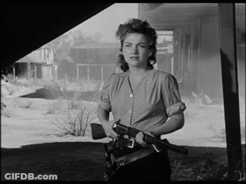 A Black And White Photo Of A Woman Holding A Gun In Her Hand . GIF