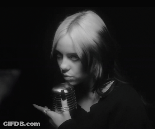 A Black And White Photo Of A Woman Holding A Microphone In Her Hand GIF