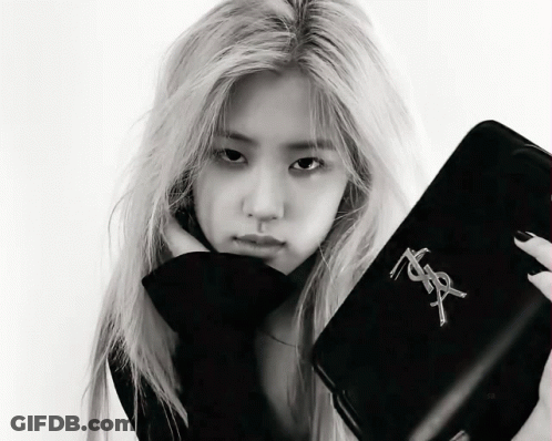 A Black And White Photo Of A Woman Holding A Purse That Says Yves Saint Laurent GIF