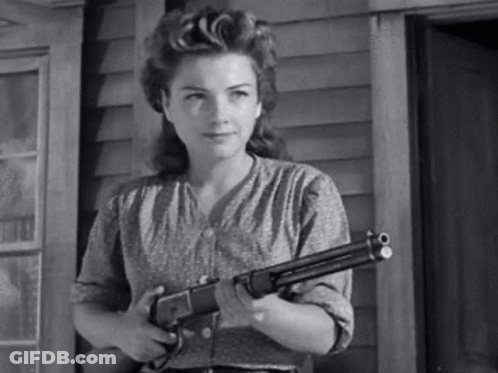 A Black And White Photo Of A Woman Holding A Shotgun . GIF