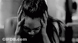 A Black And White Photo Of A Woman Holding Her Head In Pain . GIF