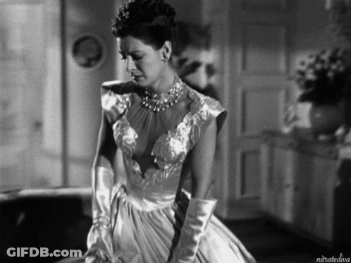 A Black And White Photo Of A Woman In A Dress And Gloves Taken By Nitratediva GIF
