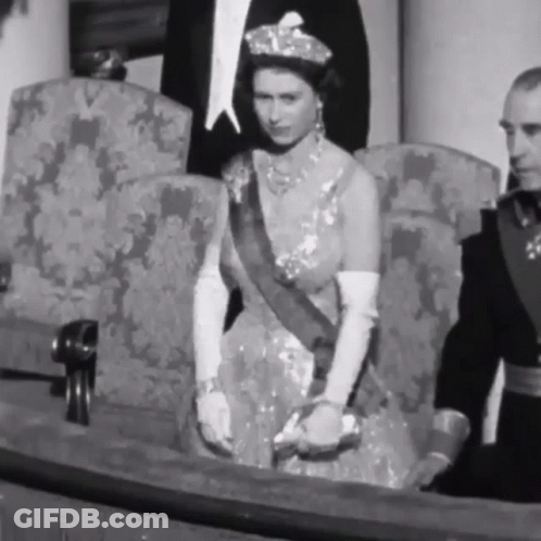 A Black And White Photo Of A Woman In A Dress Sitting In A Chair . GIF