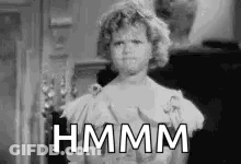 A Black And White Photo Of A Woman In A Dress With The Words `` Hmm '' Written On Her Face . GIF