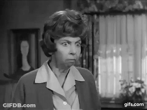 A Black And White Photo Of A Woman In A Living Room Making A Funny Face . GIF