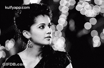 A Black And White Photo Of A Woman In A Saree Looking At The Camera . GIF