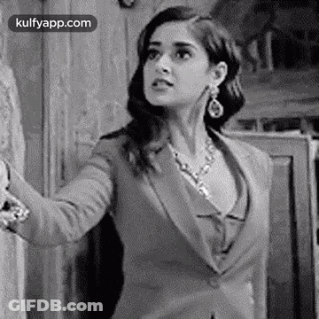 A Black And White Photo Of A Woman In A Suit And A Necklace . GIF