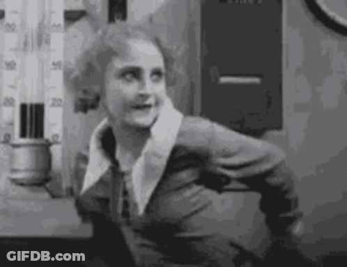 A Black And White Photo Of A Woman In A Suit Standing In Front Of A Thermometer . GIF