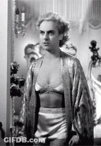 A Black And White Photo Of A Woman In Lingerie And A Robe Standing In A Room . GIF