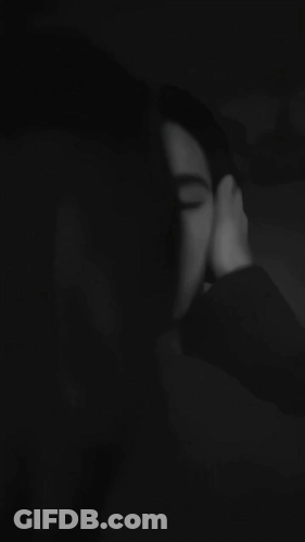A Black And White Photo Of A Woman Kissing A Man 'S Forehead . GIF