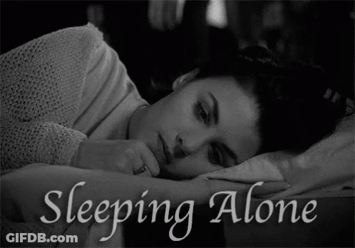 A Black And White Photo Of A Woman Laying In Bed With The Words Sleeping Alone Above Her GIF